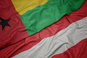 waving colorful flag of austria and national flag of guinea bissau.