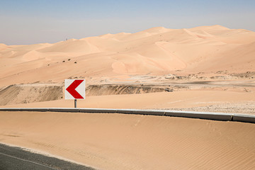 Richtungstafel in einer Kurve auf einer Wüstenstrassen in den Emiraten.