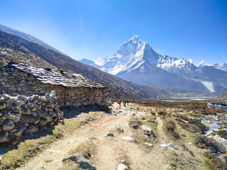 Voetpad naar het Everest-basiskamp in de buurt van een verlaten stenen huis. Ama Dablam bergtop stijgt boven de bergvallei op de achtergrond. Himalaya in de ochtend. Thema van prachtige berglandschappen.