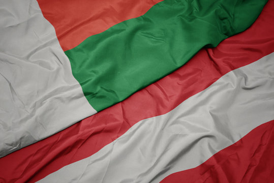waving colorful flag of austria and national flag of madagascar.