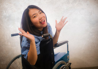 young beautiful and happy Asian Chinese woman in hospital patient gown sitting on wheelchair smiling positive recovering from accident or virus infection