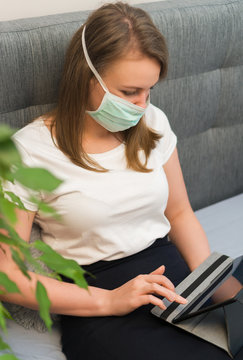 Woman in medical mask using tablet pc. Isolation at home.