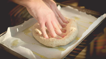Obraz na płótnie Canvas horizontal pizza dough background italian cookery hands on dough on bakin sheet olive oil homemade rustic 