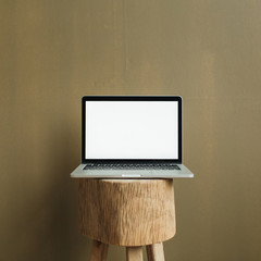 Blank screen laptop on wooden stool at tan olive background. Front view social media, website, blog...