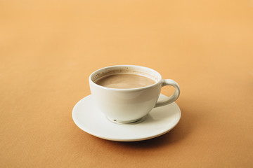 Cup of coffee with milk on ginger background.