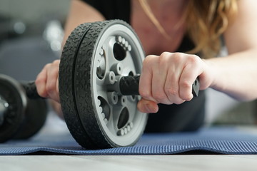 a woman exercising at home with a tummy wheel due to the gym closing, selective Focus, closeup
