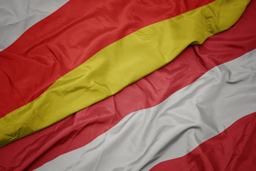 waving colorful flag of austria and national flag of south ossetia.