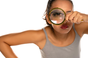a suspicious young woman looks through a magnifying glass