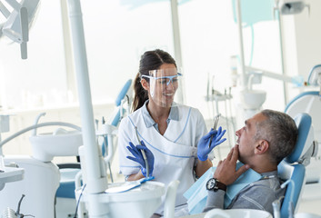 Dentist in dental office talking with male patient and preparing for treatment.	
