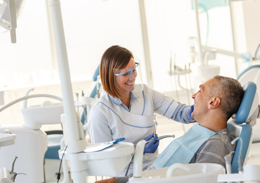 Dentist in dental office talking with male patient and preparing for treatment.	