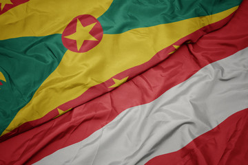 waving colorful flag of austria and national flag of grenada.