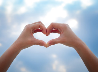 Heart symbol from hands on the blue sky background, Concept for Love or Health.
