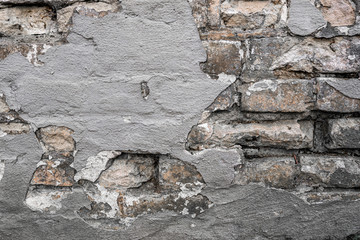 Old grey brickwall with flaked off colour