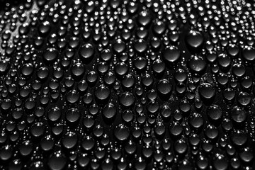 Minimalistic abstract black trendy background. Small drops of water on a dark surface.