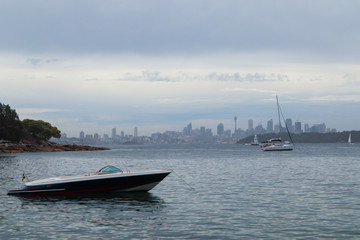 Fototapeta premium Lonely boat on water with the city on the horizon