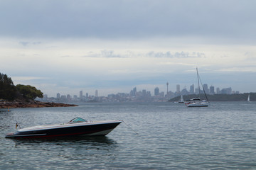 Lonely boat on water with the city on the horizon