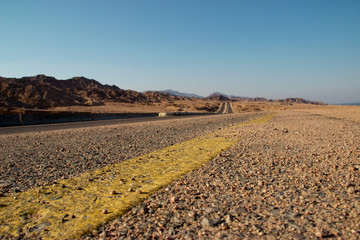  long road in the desert with the blue and clear sky