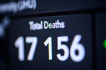 White Number of Total Deaths . Coronavirus COVID-19 global cases Map. Red Dot showing the number of infected. Johns Hopkins University map on monitor display.