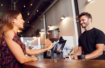 Female Customer Paying Barista At Coffee Shop Sales Desk