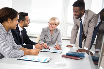 International group of business people working and communicating sitting near office desk.