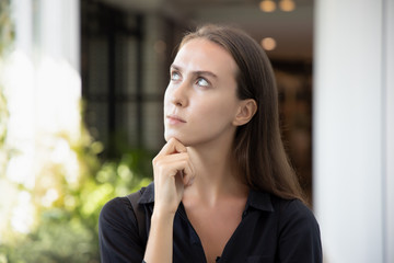 Fototapeta na wymiar stressed upset thoughtful white caucasian woman thinking, planning about problem; portrait of woman looking up, thinking, finding good idea or decisive plan; young adult Russian caucasian woman model