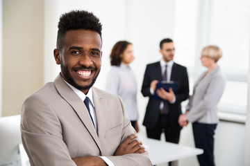 Portrait of african-american businessman and his colleagues on the background at the office