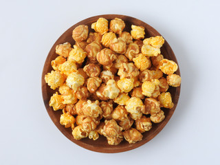 Top view of delicious popcorn in round wooden plate isolated on white background. Include buttery caramel corn and rich cheddar cheese corn. Food and snack concept.