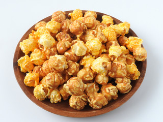 High angle view of delicious popcorn in round wooden plate isolated on white background. Include buttery caramel corn and rich cheddar cheese corn. Food and snack concept.
