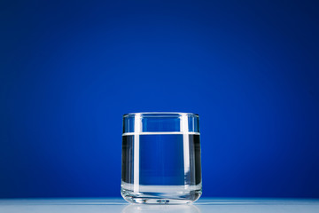 Glass of still water isolated on blue background