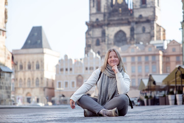 Fototapeta premium Girl sitting on the cobbles of an empty old town square in Prague. Czech Republic
