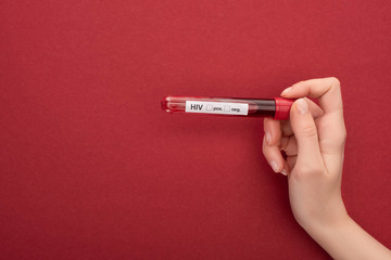 cropped view woman holding blood sample in test tube with hiv lettering on red background