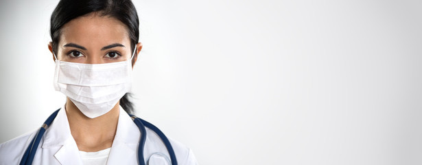 Сlose-up face of serious hispanic female doctor оn a gray background for your text.