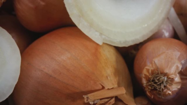 A 4K Shot of Fresh Onions that has just been cut. A shot showing the layers of an onions insides. Multiple uncut onions amongst sliced layers of onions. Agriculture. Macro Shot.