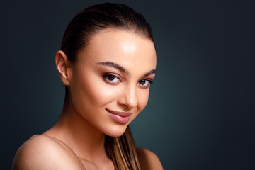 Closeup portrait of beautiful young woman with nice and clean skin with subtle makeup on a dark background