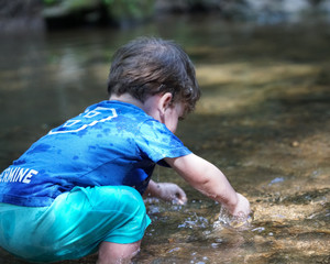 toddler  playing in a river