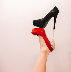 fashionable background for advertising shoes, red and black shoes on the foot in an unusual interesting position with a white background