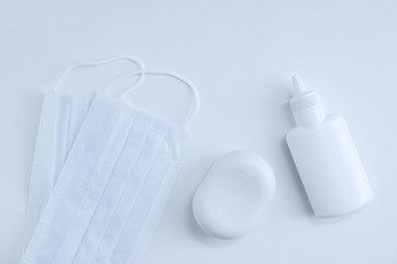 Protective cloth face mask, disinfectant in bottle and bar of soap on a white background close-up.