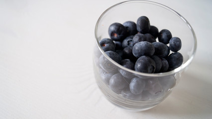 tasty and very useful blueberry berry. Frozen blueberries on a white photo in a glass.