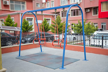 Fototapeta na wymiar Wooden and Empty red and blue chain swings in children playground . chain swings hanging in garden . Childs swing in a park .