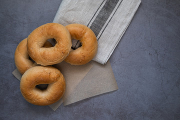Bagels on baking paper and a cloth in concrete background. Top view. Copy space.