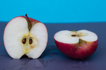 Sliced red apple on a wet surface