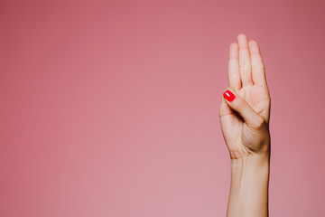 Woman's hand with bright manicure isolated on pink background three fingers up