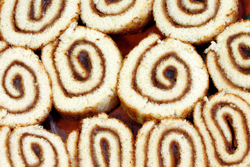 Swiss sweet roll with jam on a plate, slices of homemade sponge roll cake on a plate.