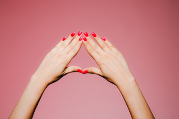 Woman's hands with bright manicure isolated on pink background triangle sign