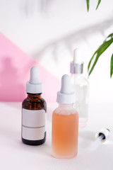 Various bottles for cosmetics, natural medicine, essential oils or other liquids isolated on a white table against duotone background.