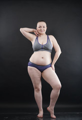 Obraz premium plus size woman shows her body in stretch marks and hair with cellulite and encourages you to love and accept yourself in any way . black background in the Studio. full- length photo.