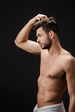 sexy handsome man in towel combing hair isolated on black