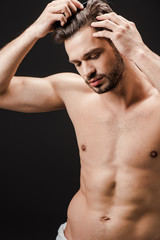 bearded handsome nude man combing hair isolated on black