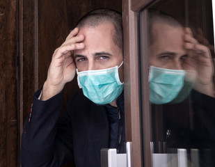 uomo con mascherina prova ad uscire di casa con atteggiamento cauto  
