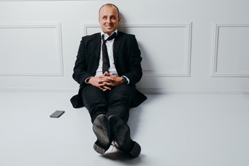 Happy young businessman sitting on floor dreaming